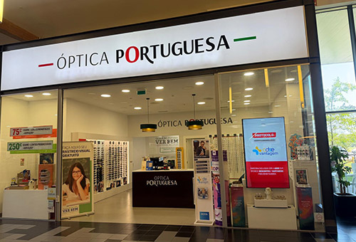 Storefront of Óptica Portuguesa eyewear shop with a bright interior and display stands visible through the entrance.