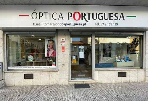 Storefront of Óptica Portuguesa eyewear shop with a large sign above the entrance and window displays.